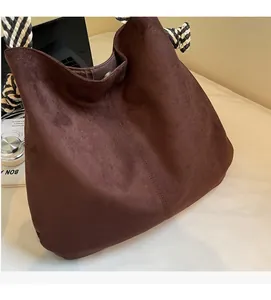 Detail of dark brown suede hobo bag with black and white woven rope shoulder strap