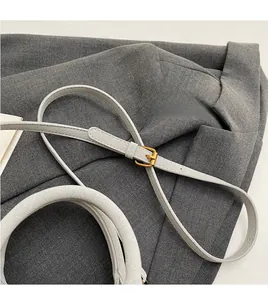 Detail of adjustable light gray leather shoulder strap with lychee texture and gold buckle