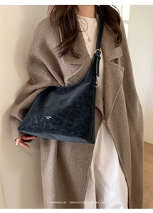 Detail of vintage charcoal grey hobo bag with matte texture on model in camel coat