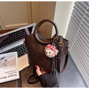 Détail du sac seau rétro marron foncé avec poignée ronde et breloque ours en peluche