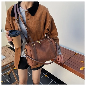 Détail du sac Boston en daim marron avec ferrures dorées et bandoulière en cuir chic