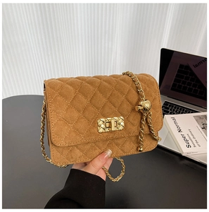 Detail of caramel brown suede crossbody bag with quilted pattern and gold metal lock
