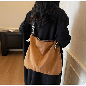 Detail of a large brown suede tote bag with stylish black and white striped woven straps
