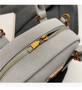 Close-up of smooth bronze zipper and pebbled gray leather on the minimalist handbag