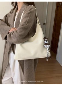 Detail view of white minimalist tote bag with a dog charm and soft leather texture