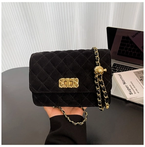 Detail of black quilted velvet crossbody bag featuring golden chain and metal turn-lock
