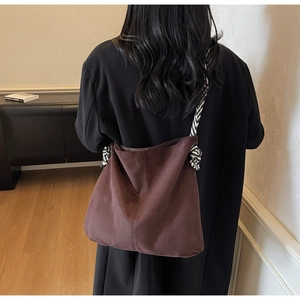 Detailed back view of a brown suede tote bag with a unique black and white woven strap