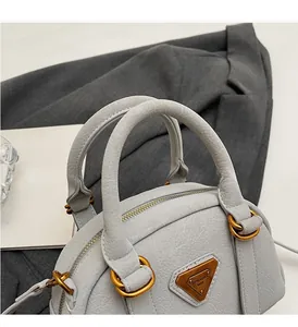 Detail of light gray textured leather bowling bag with gold metal rings and top handles