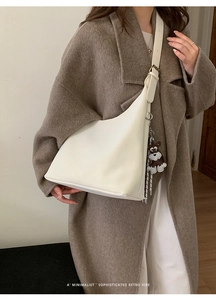 Detailed view of white hobo bag with matte finish and cute brown puppy charm accessory