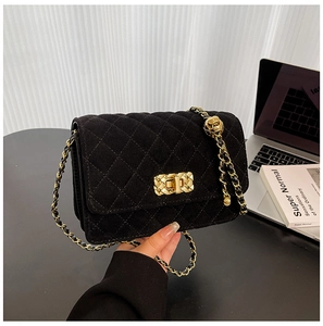 Close-up of quilted black suede crossbody bag with gold chain and floral metal ball
