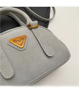 Detail of light gray leather Boston bag showing grain texture and gold triangle logo