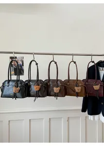 Détail de sacs cabas vintage en cinq couleurs avec breloques d'ours et logo gravé