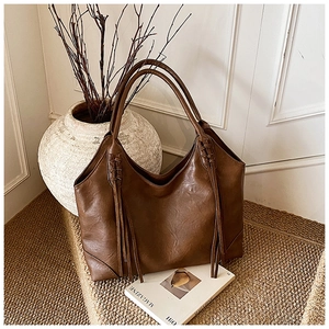 Détail d'un sac cabas marron vintage avec textures tissées et accents de glands