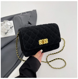 Detail of classic quilted velvet crossbody bag with golden metal twist lock and chain strap