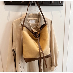 Detail of suede tote bag with leather trim and drawstring on a beige trench coat