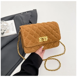 Detailed close-up of brown suede quilted crossbody bag with gold chain and metal lock