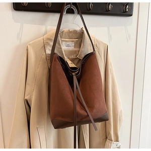 Brown suede tote bag with contrast leather base hanging over a trench coat