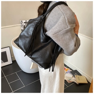 Détail d'un grand sac cabas noir avec des pompons en cuir dans un cadre élégant et chic