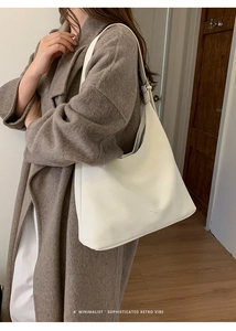 Model wearing a minimalist cream leather hobo shoulder bag with a vintage cracked texture