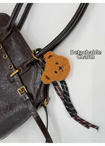 Détail du sac à main rétro marron foncé avec boucle dorée et pendentif ours amovible