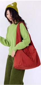 Detail of red nylon shoulder bag with drawstring closure styled with casual winter outfit