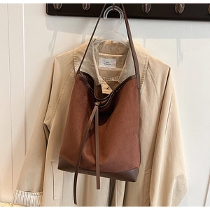 Brown suede bucket bag detail with dark leather trim and drawstring on trench coat