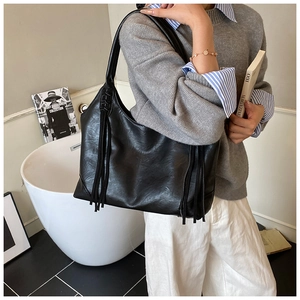 Détail du sac hobo en cuir noir avec de longues franges et une texture grainée douce