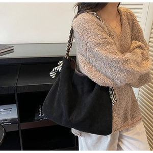 Detail of black suede tote bag with stylish black and white striped woven strap