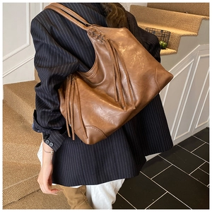 Détail du grand sac cabas en cuir marron avec de longues franges porté par mannequin
