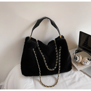 Détail d'un sac bandoulière en fausse fourrure noire avec chaîne dorée et cuir