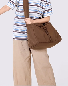 Brown nylon crossbody bag with side drawstring details and wide shoulder strap shown on model