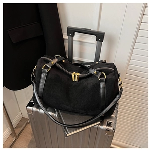 Détail du sac boston en daim noir avec fermetures dorées et poignées en cuir de qualité