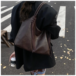 Grand sac cabas marron foncé en similicuir avec franges dans un décor de style urbain