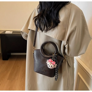 Détail d'un sac à main en cuir marron avec poignée demi-lune et logo doré élégant