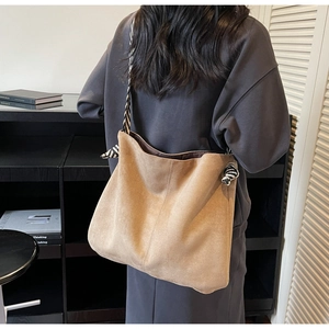 Minimalist khaki suede tote bag with striped shoulder strap shown on a model