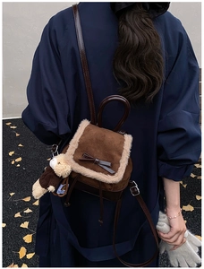 Mini brown suede backpack with faux fur trim and bow detail shown on model in autumn