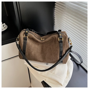Détail du sac Boston en daim marron foncé avec lanières en cuir noir et boucles dorées