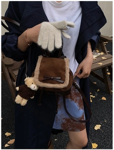 Detail of a brown suede mini backpack with faux fur trim and cute teddy bear charm