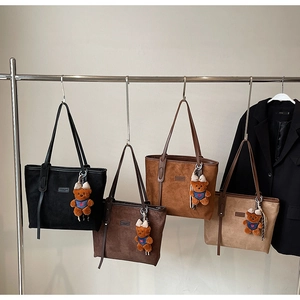 Detail view of four large suede tote bags in various colors on a sleek metal hanger
