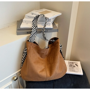 Close-up of brown suede hobo bag featuring black and white striped rope shoulder strap
