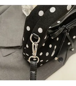 Gros plan détaillé des ferrures argentées sur un sac à main en daim noir à pois blancs