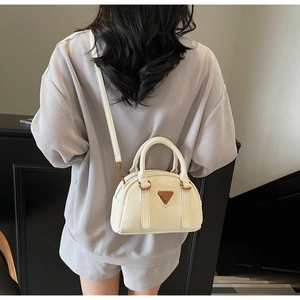 Chic cream bowling bag with pebble grain leather texture shown on person