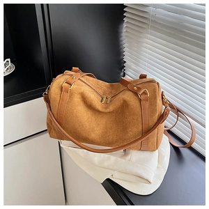 Détail du sac Boston en daim caramel avec finitions en cuir et boucles dorées