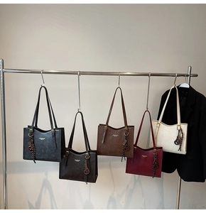 Close-up of five colorful large-capacity tote bags hanging on a rack for display