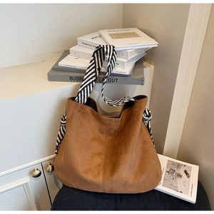 Detail of dark brown suede tote bag featuring black and white striped knotted shoulder strap