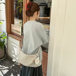 Borsa a mezzaluna in nylon beige con tracolla regolabile e ciondolo a forma di coniglio