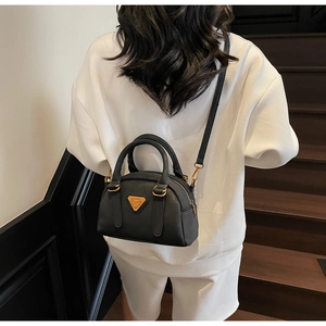 Rear view of a model carrying a black leather Boston bag with gold hardware details