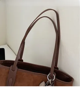 Detail of the smooth leather shoulder strap and silver metal ring on the brown suede tote