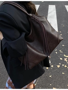 Sac hobo marron foncé rétro avec franges et bandoulière tressée porté à l'épaule