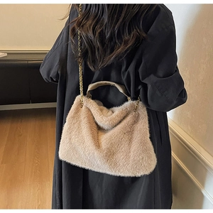 Détail du sac à main en peluche avec poignée en cuir et chaîne dorée sur manteau noir